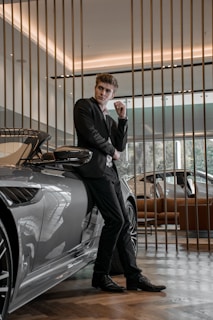 man in black suit standing beside silver car
