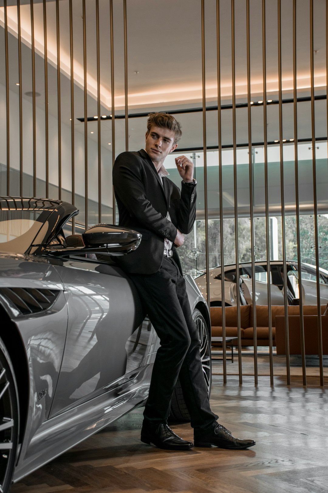 man in black suit standing beside silver car