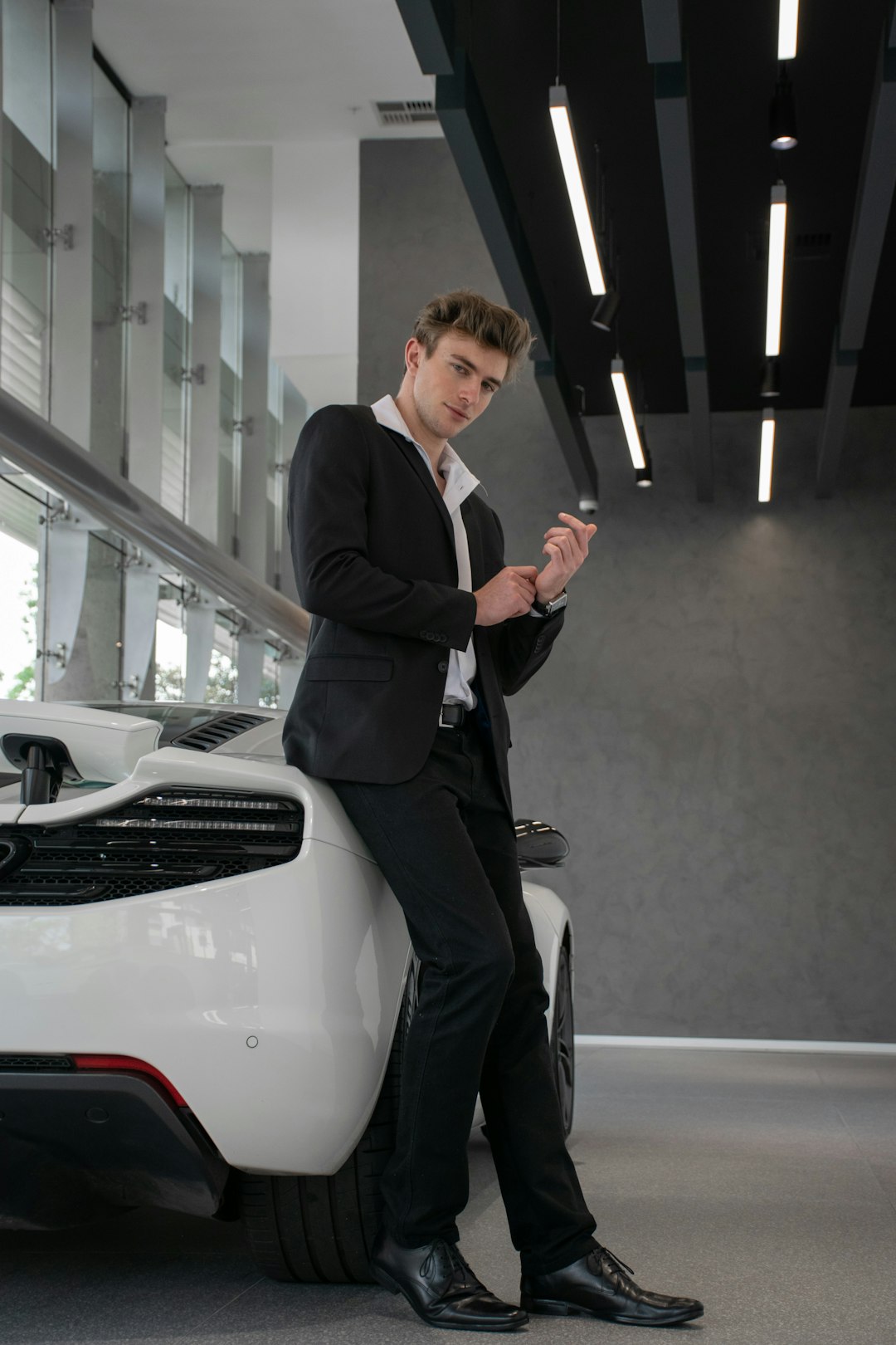 man in black suit jacket and pants standing beside white car
