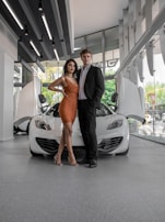 woman in black sleeveless dress standing beside white car