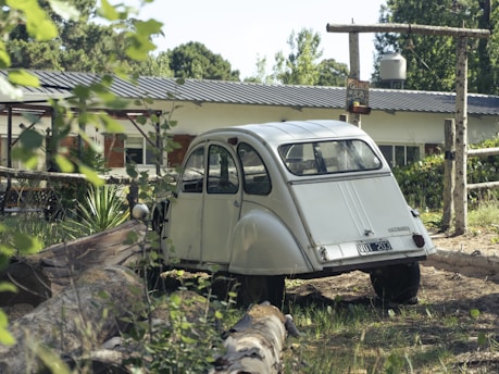 A vintage Fiat 600 parked in a serene countryside setting, surrounded by greenery.