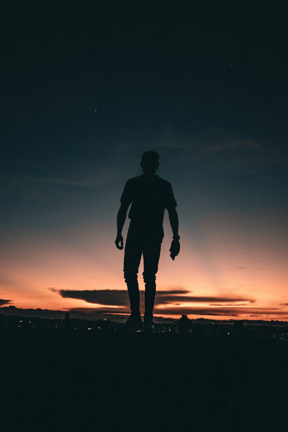silhouette of man standing on top of hill during sunset