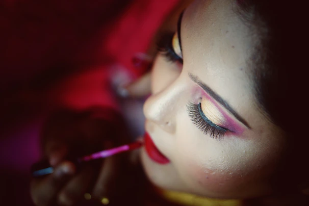 Close-up of a stylist carefully applying makeup on a smiling client.