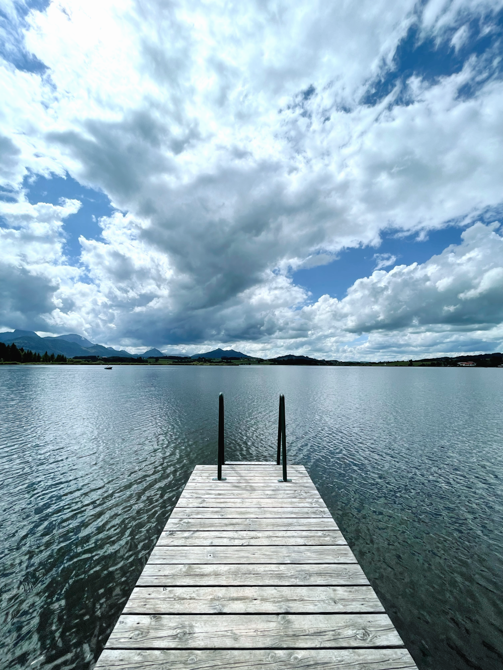 brown wooden dock on body of water under blue and white cloudy sky during daytime