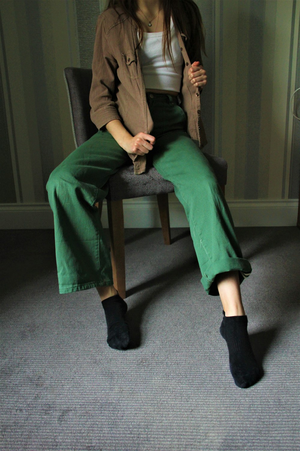 woman in green blazer and black pants sitting on brown wooden armchair