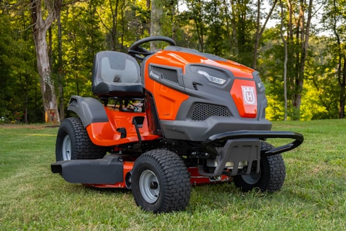 orange and black ride on lawn mower on green grass field during daytime