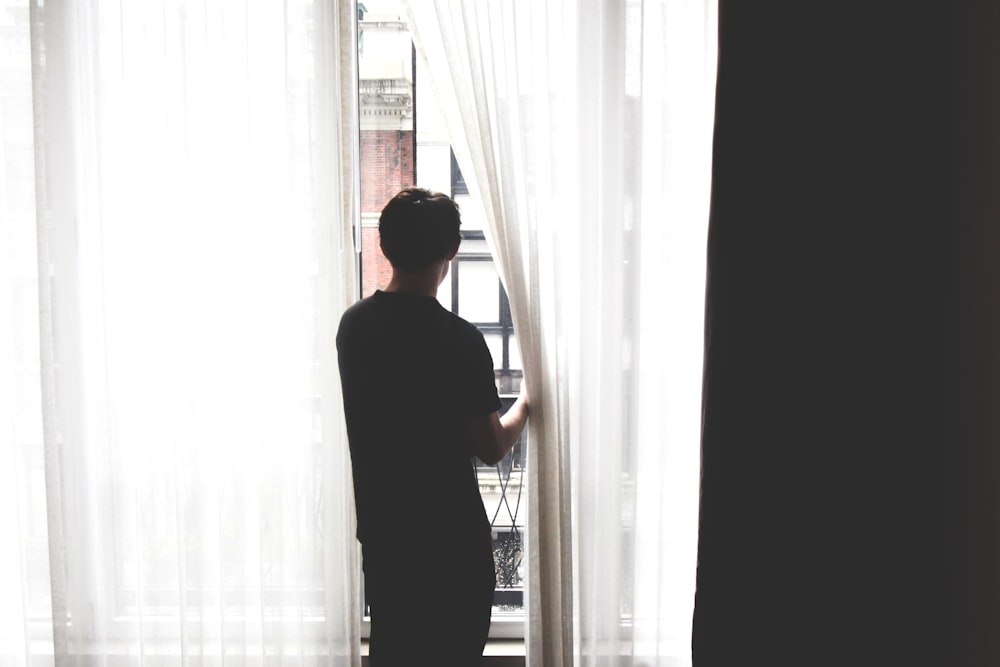 a man standing in front of a window looking out