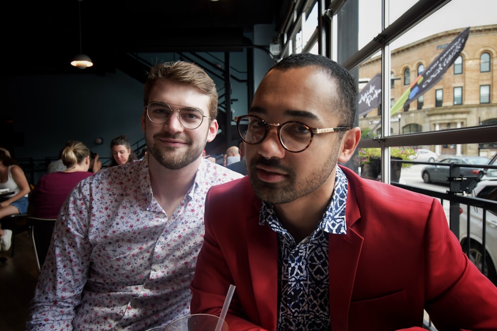 man in red suit jacket beside woman in white and purple floral dress