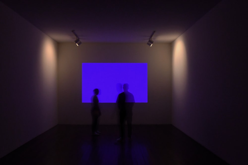 a couple of people standing in a room with a purple light