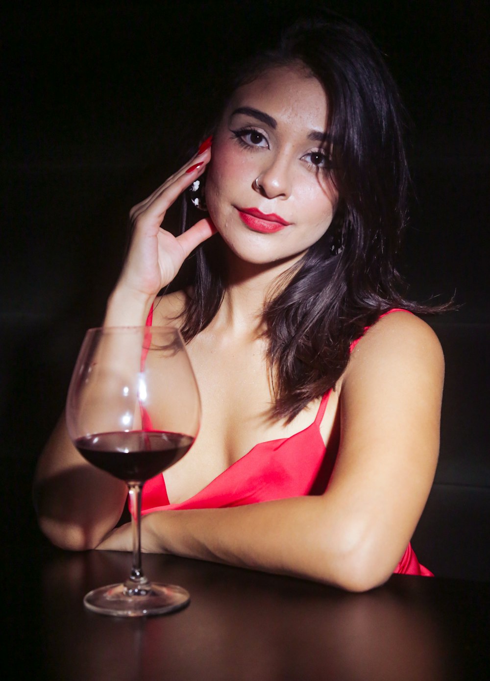 femme en débardeur rouge tenant un verre de vin