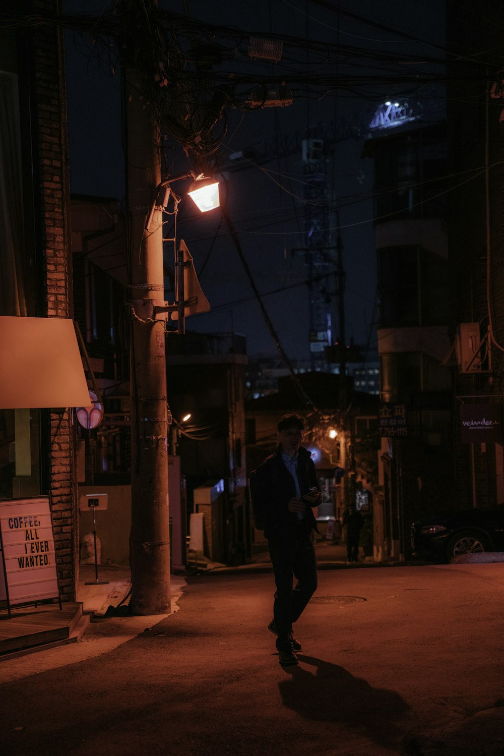 homem em jaqueta preta e calças andando na rua durante a noite