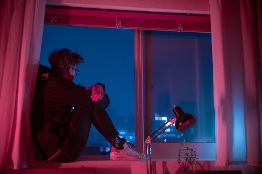 woman in black jacket sitting on window