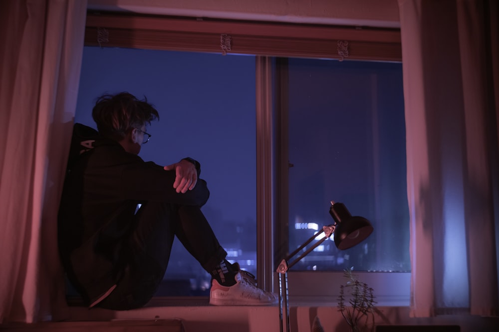 woman in black jacket sitting on window