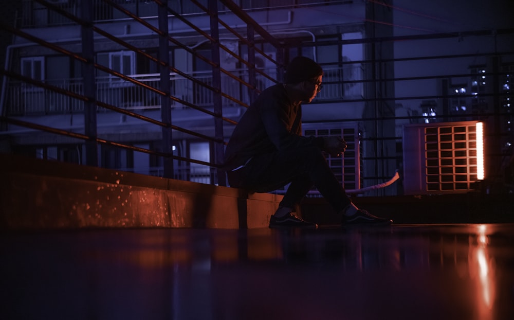 man in black jacket and pants sitting on red floor