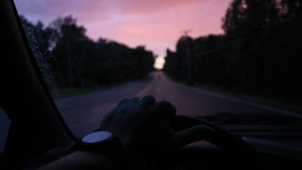 person driving car on road during sunset