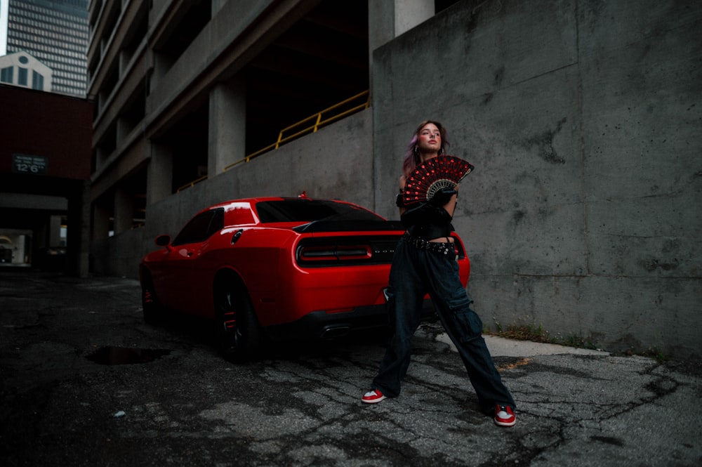 a woman standing next to a red sports car