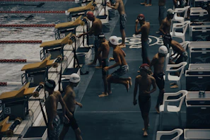 Close-up of colorful swim caps and goggles lined up on the pool deck before practice