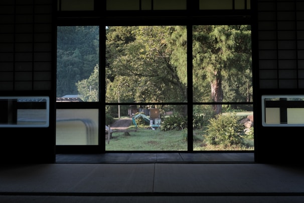 A cozy tatami room with sliding doors opening to a garden showing autumn foliage.