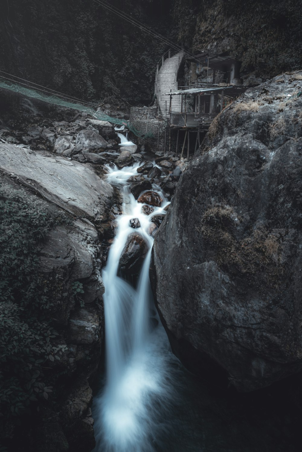 water falls between rocky mountain during daytime