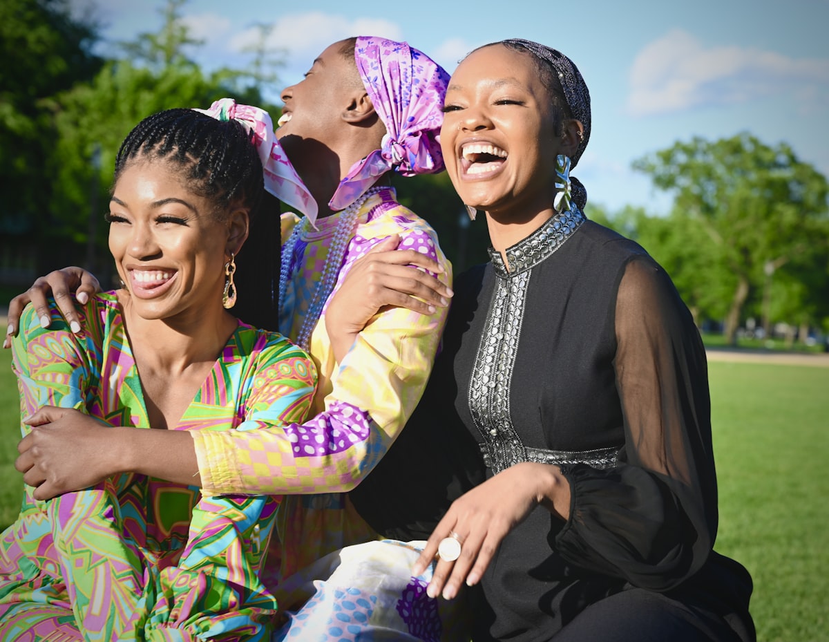 Mature Black women friends laughing together in colorful attire - sisterhood community