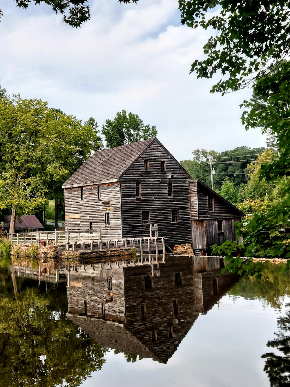 brown wooden house near green trees and river during daytime