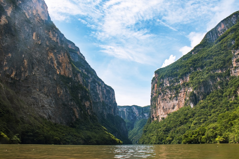 montanha verde e marrom ao lado do corpo de água sob o céu azul durante o dia