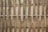 An arrangement of vertical and horizontal bamboo sticks forms a traditional woven fence. The bamboo appears natural and untreated with variations in color and texture, giving it a rustic yet organized look.