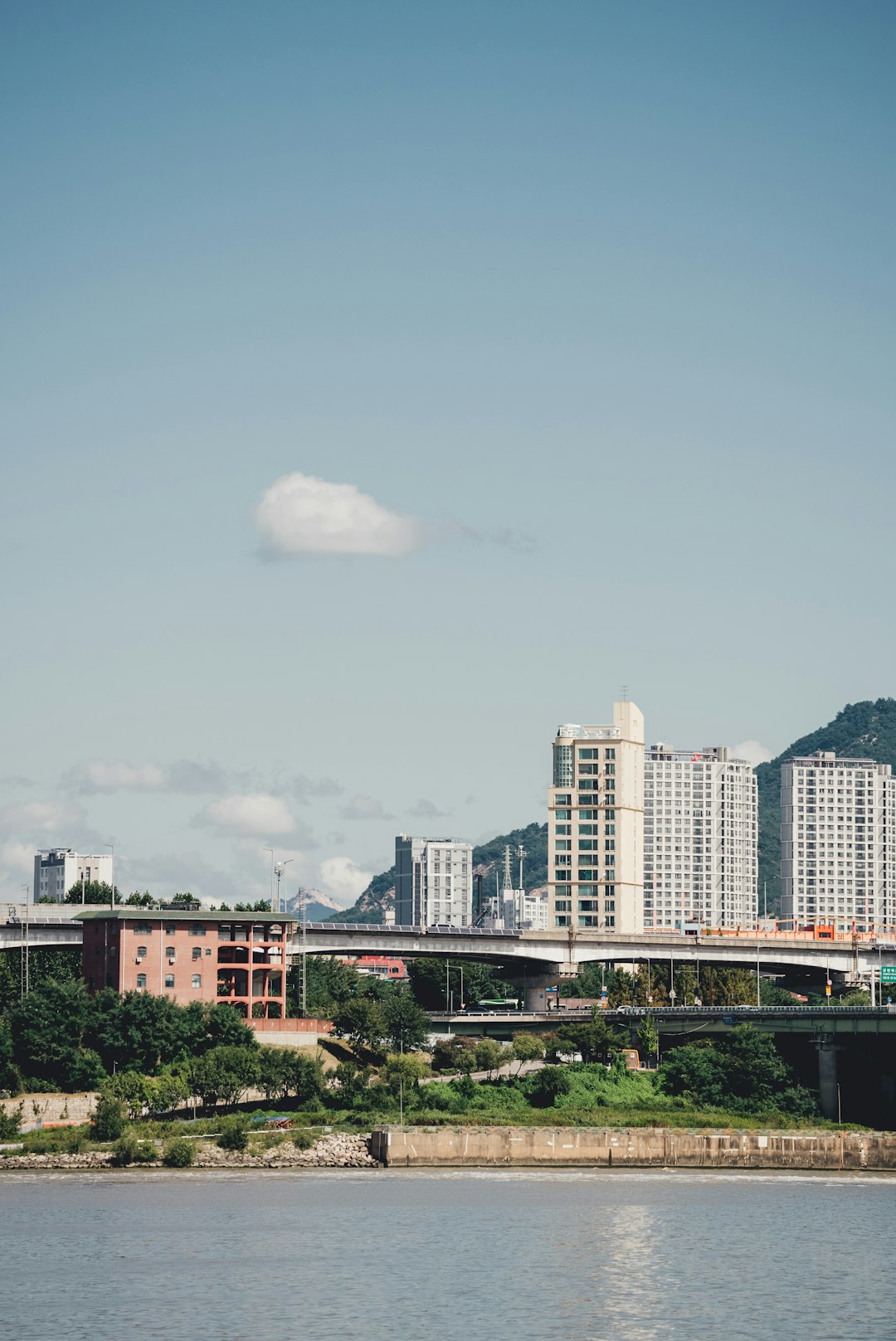 white concrete building near green trees under white clouds during daytime