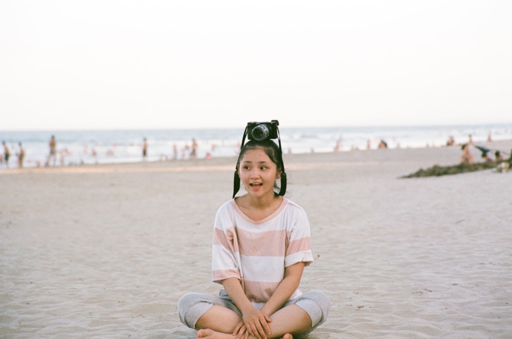 girl in white shirt sitting on sand during daytime