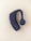 A black Bluetooth earpiece with a sleek design is placed on a light beige background. The earpiece has an ergonomic shape with a circular speaker grill featuring a concentric pattern.