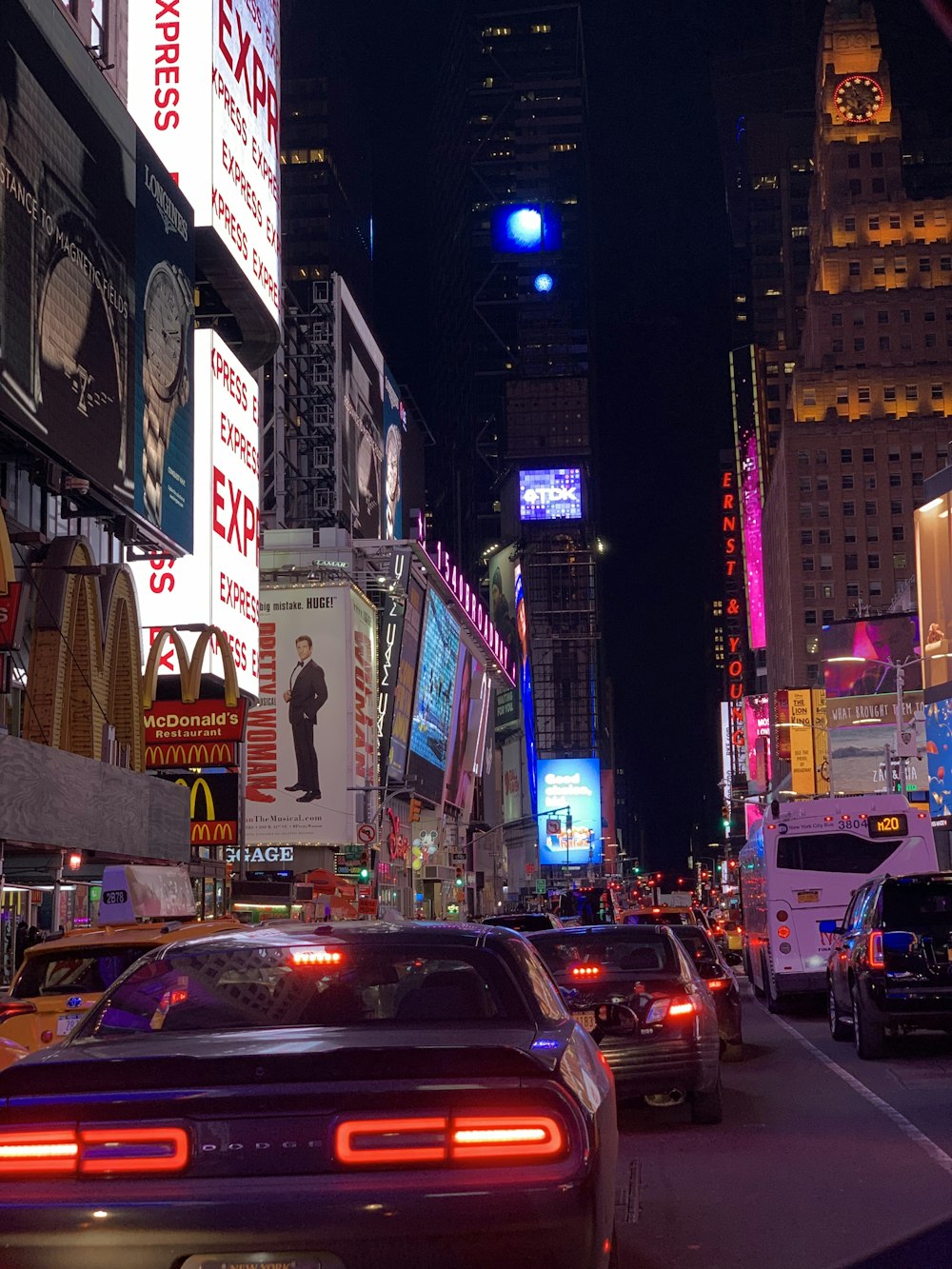 cars on road between high rise buildings during night time