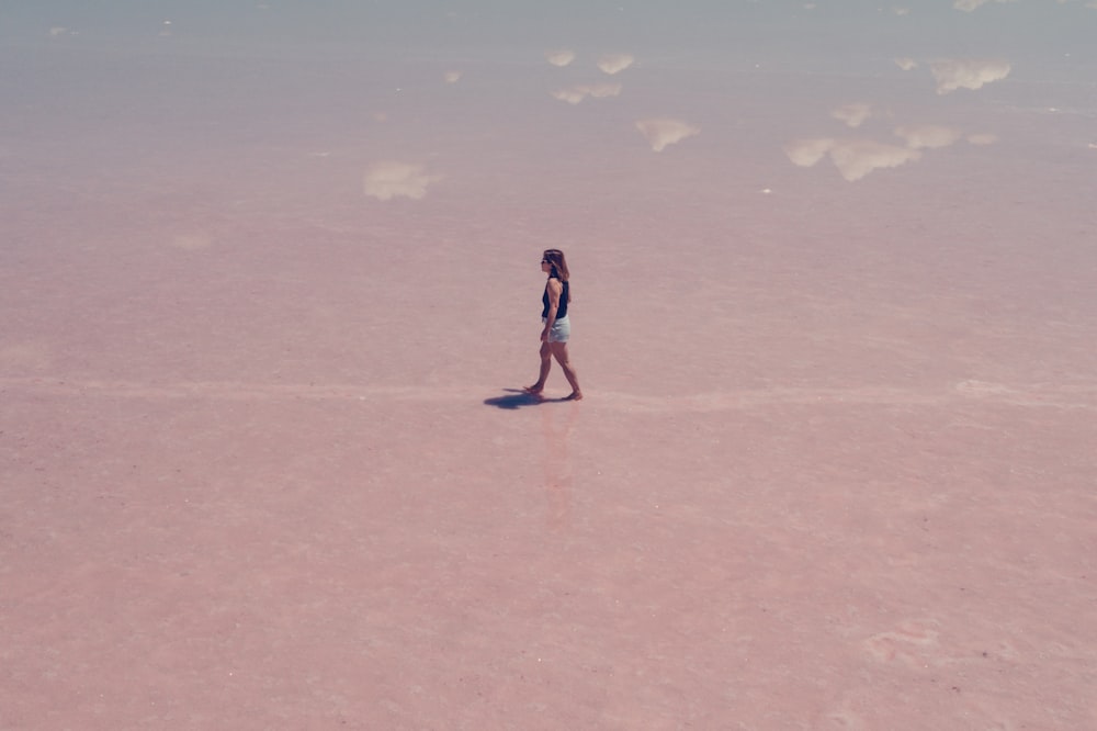 woman in black and white dress walking on brown sand during daytime