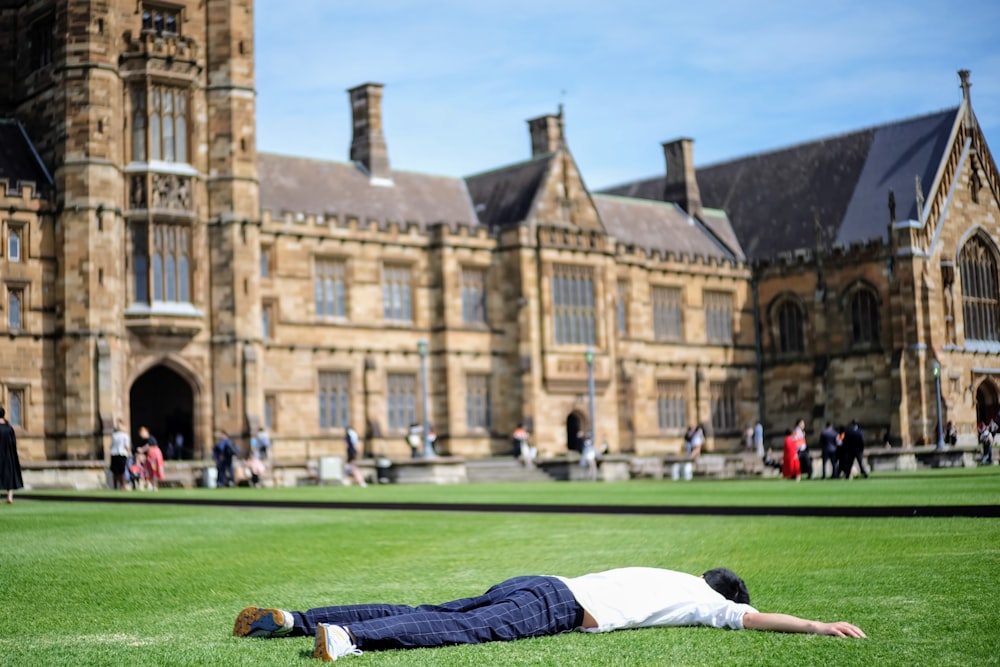 man in white t-shirt and black pants lying on green grass field