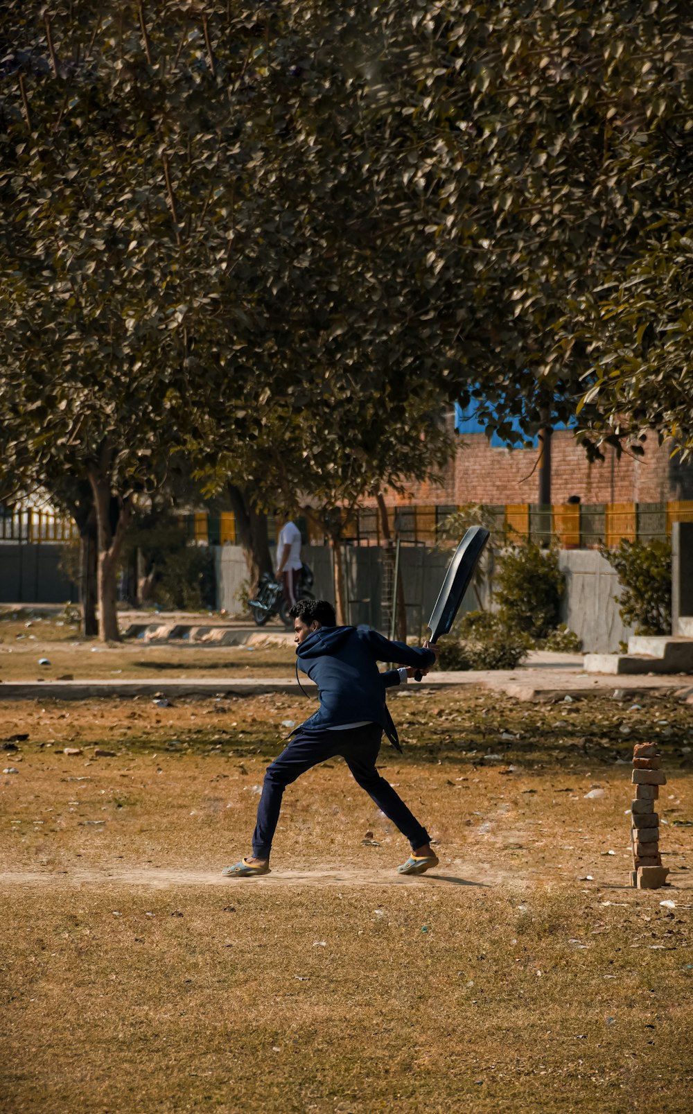 man in black jacket and blue denim jeans holding black and white sword