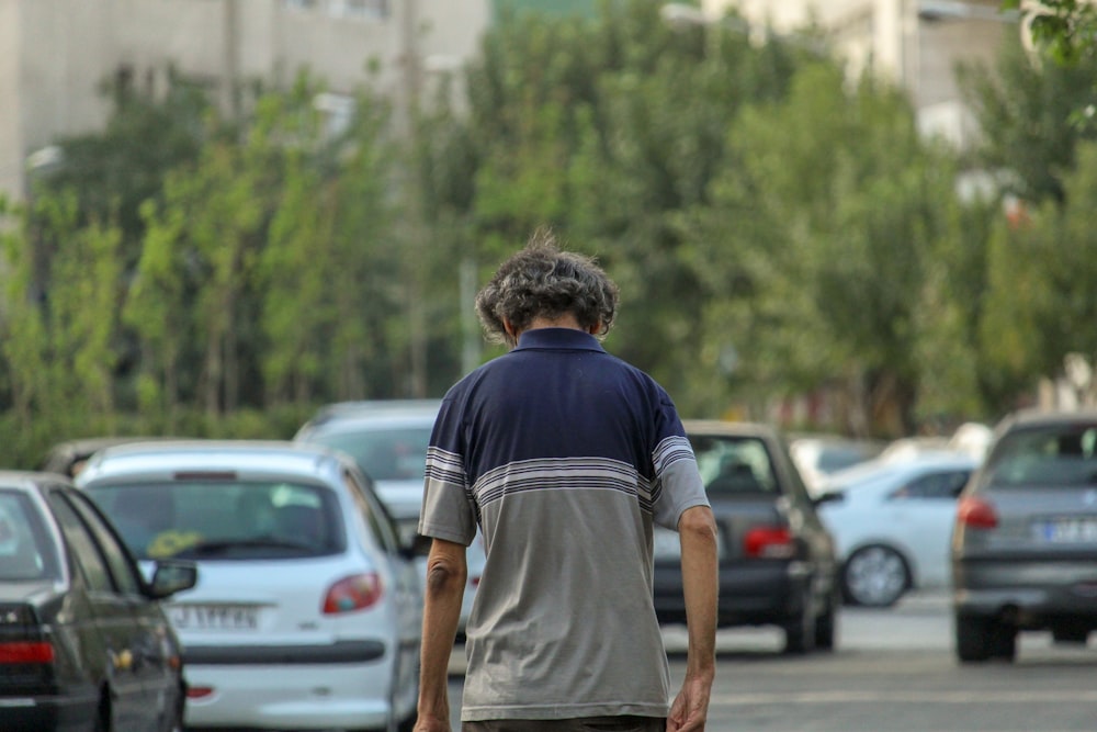 man in black t-shirt and brown shorts standing near cars during daytime