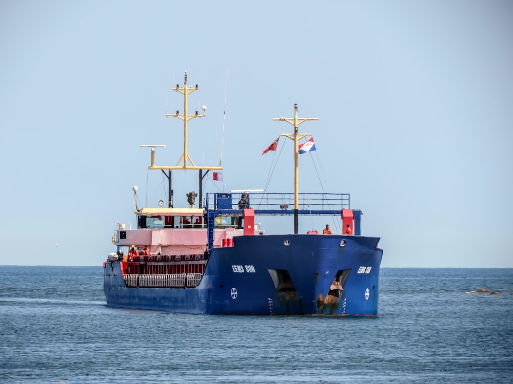 blue and red ship on sea during daytime