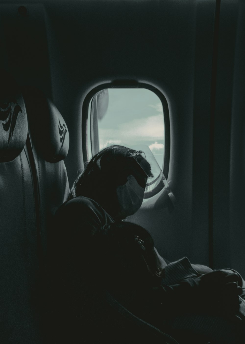 person in black jacket sitting on airplane seat
