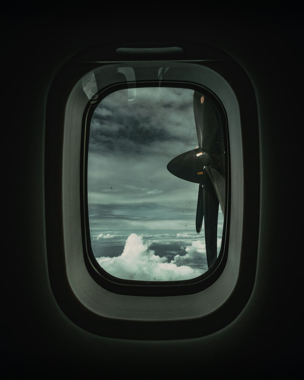 airplane window showing white clouds during daytime