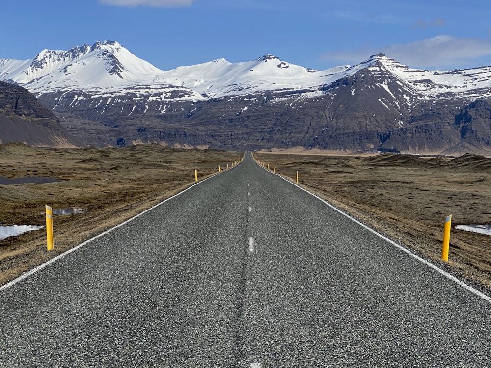 gray concrete road near snow covered mountain during daytime
