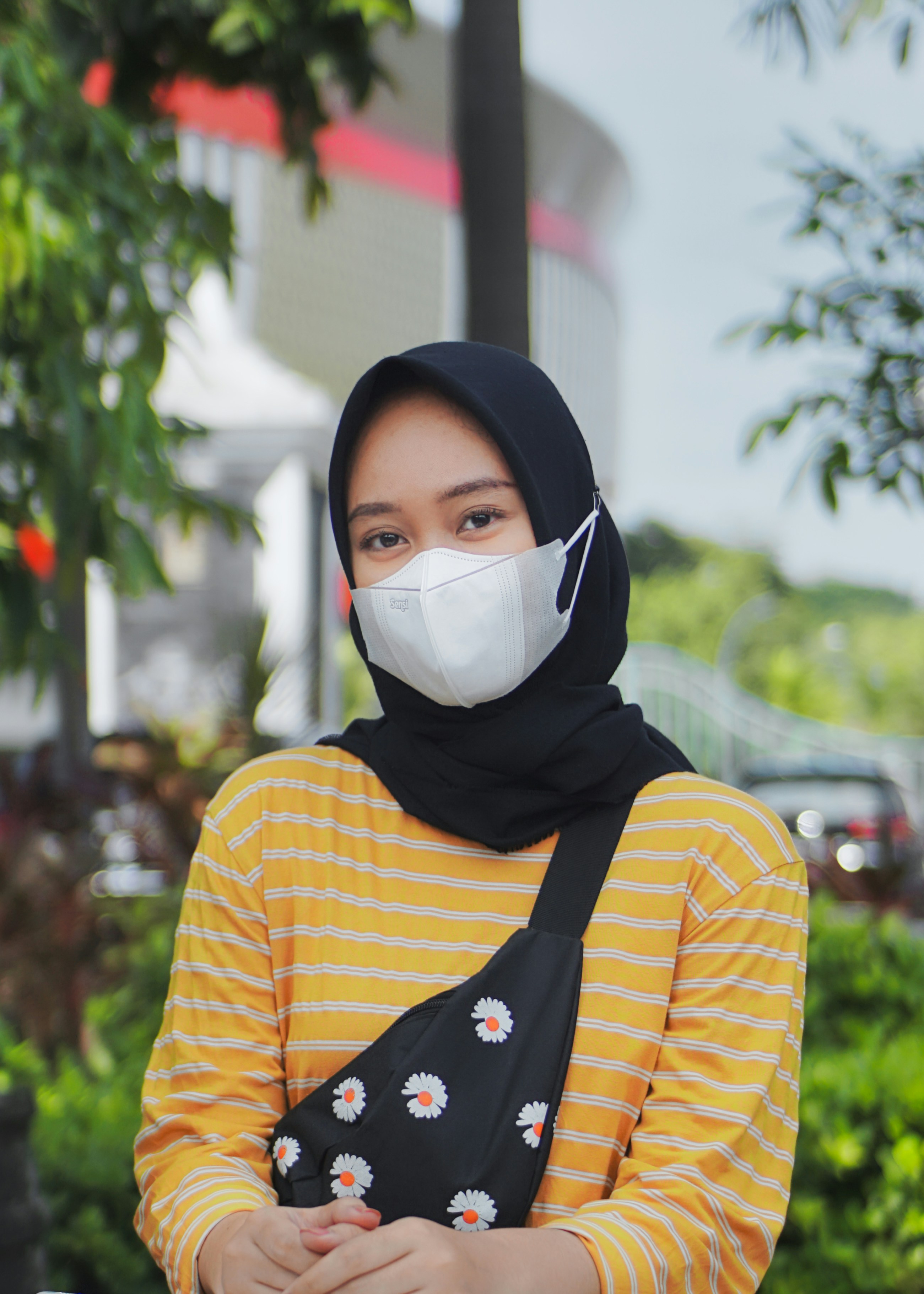 Frau in orange-weiß gestreiftem Langarmhemd mit schwarzem Hijab