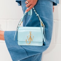 person in blue denim jeans holding white leather handbag