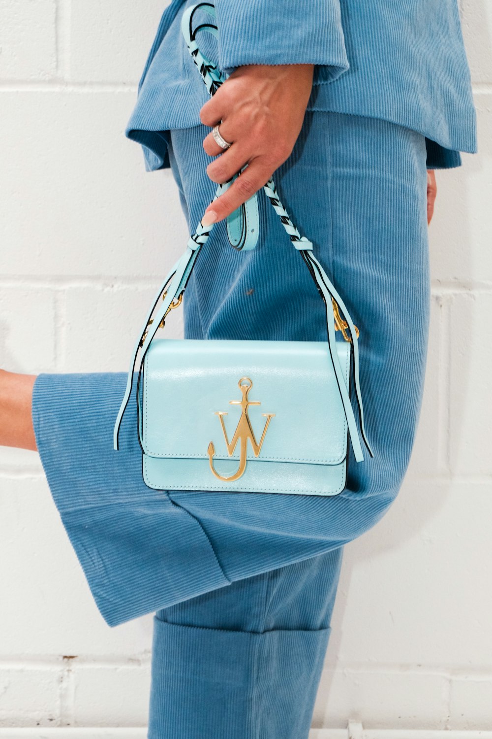 person in blue denim jeans holding white leather handbag