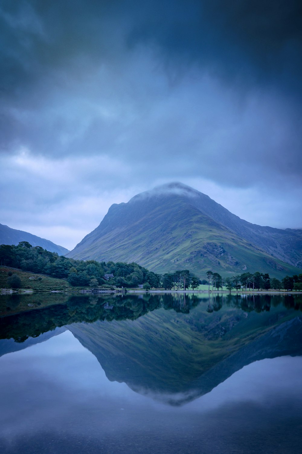 green mountain beside lake under cloudy sky during daytime