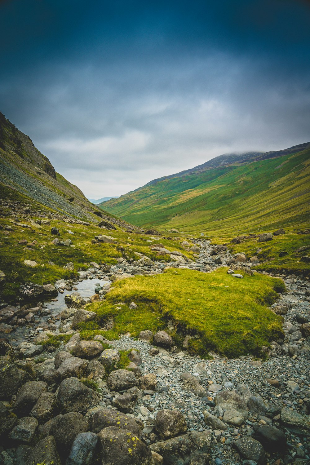 green grass covered mountain under cloudy sky during daytime