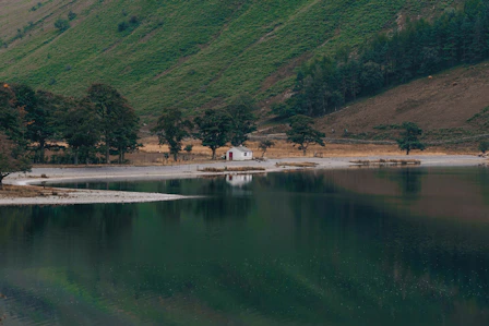 green mountain beside body of water during daytime