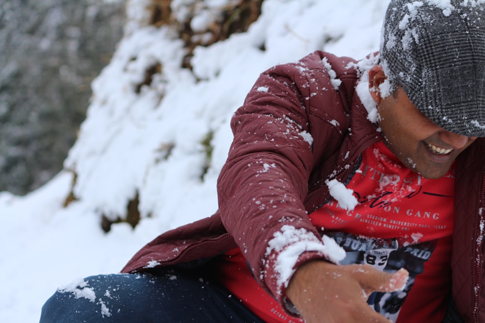 a man sitting in the snow with his hand on his hip