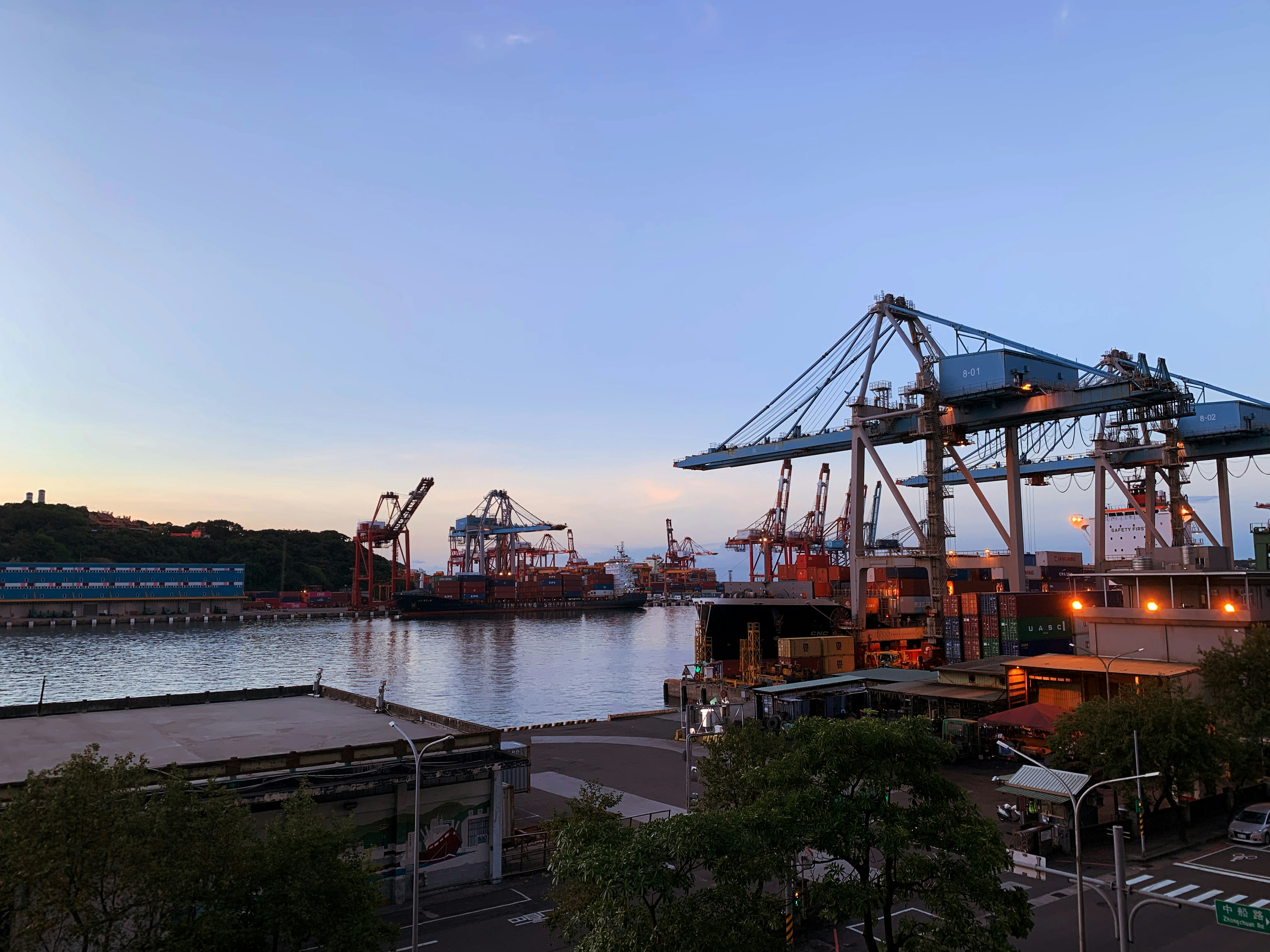 Container ship being loaded at a port with large cranes, industrial maritime logistics operations