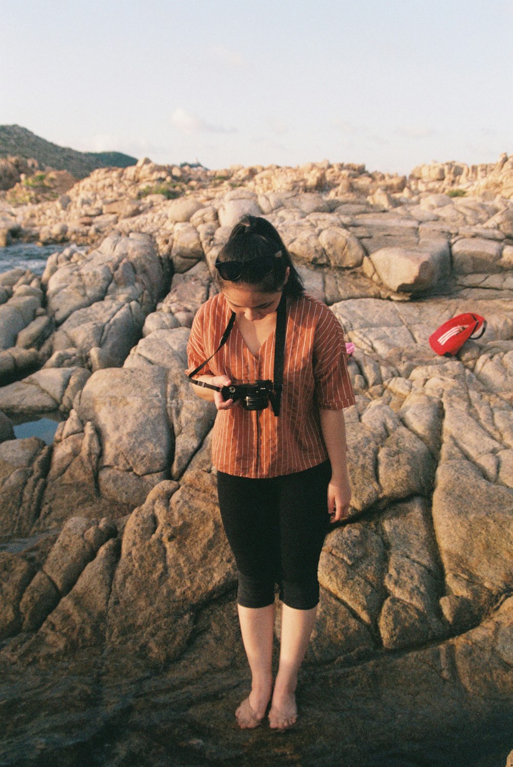 Femme en jupe noire debout sur le rivage rocheux pendant la journée