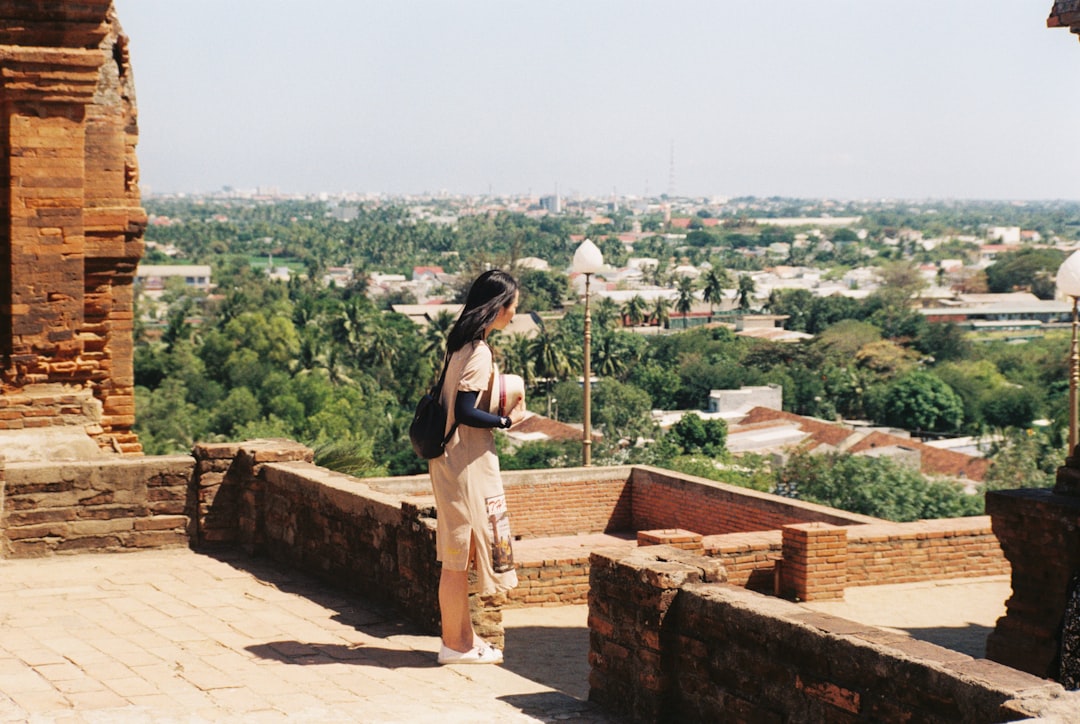 woman in black t-shirt and brown pants standing on brown concrete bricks during daytime