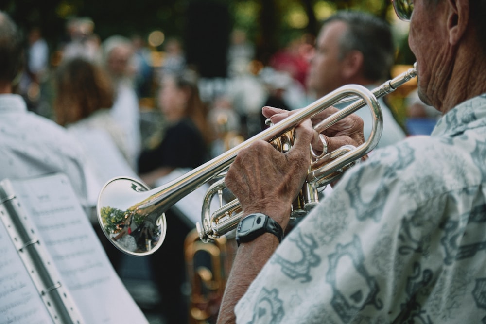 man in white and black floral shirt playing trumpet